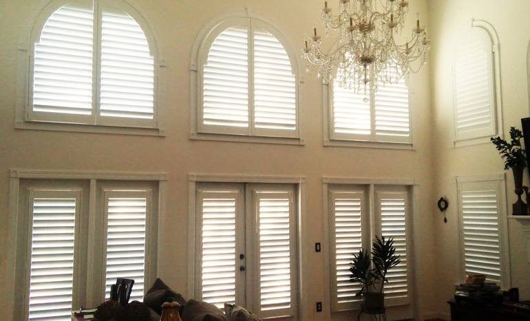 Great room in two-story San Antonio home with plantation shutters on high windows.