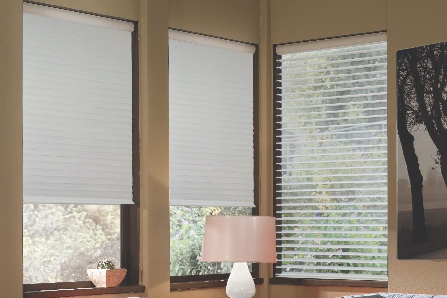 Opaque motorized window shades in San Antonio keep hot UV rays out of your home. Gray motorized sheer shades on corner windows next to gray furniture