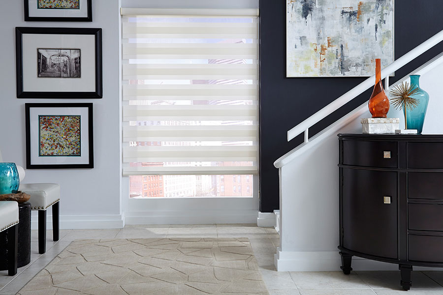 White transitional shades on a large window next to a staircase