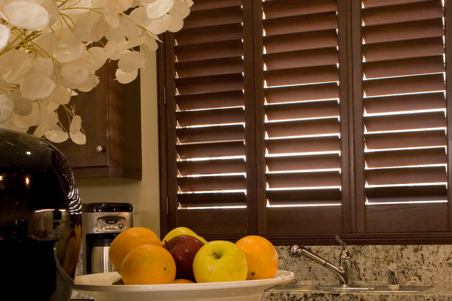 Dark wood shutters above a kitchen sink.