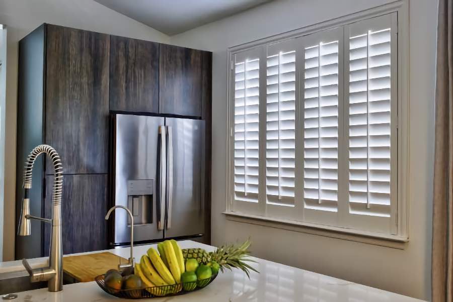 Homeowners use indoor window shutters in San Antonio when they want attractive and functional window treatments. Polywood shutters on a large kitchen window