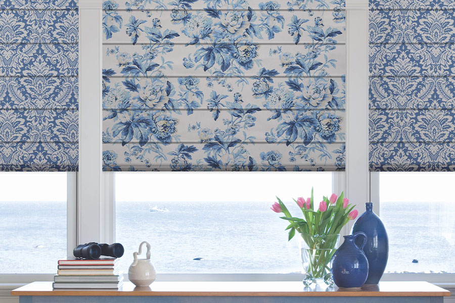  Blue and white patterned Roman shades on a window overlooking the ocean