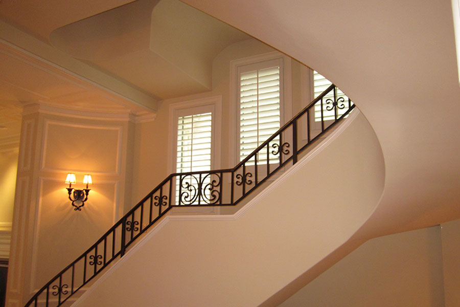 Use the same window treatments on all of your stair windows. Polywood shutters are an elegant choice. Polywood shutters on three windows in an ornate stairwell