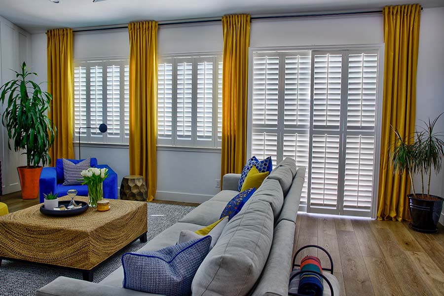Interior shutters fit on all kinds of doors without getting in the way when you go in and out. White Polywood shutters on a sliding glass door in a family room