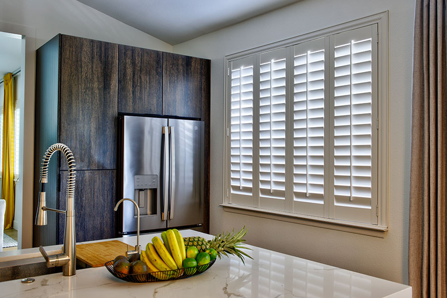 Energy-efficient Polywood shutters insulate your windows and keep your home a comfortable temperature. White Polywood shutters on a large kitchen window