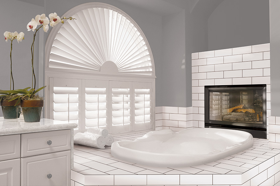 Explore our selection of window treatments for builders in San Antonio to find the perfect ones for your next construction project. White Polywood shutters on an arched bathroom window