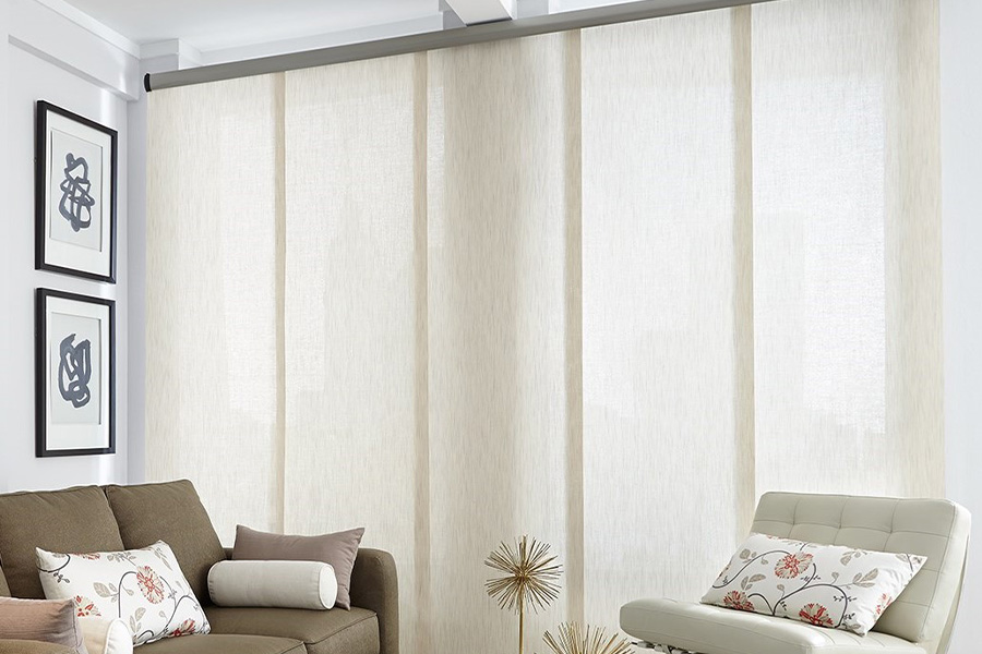 Find window treatments to complete any interior design among our extensive selection at Sunburst Shutters San Antonio.  Long off-white window shades on a tall window in a modern living room