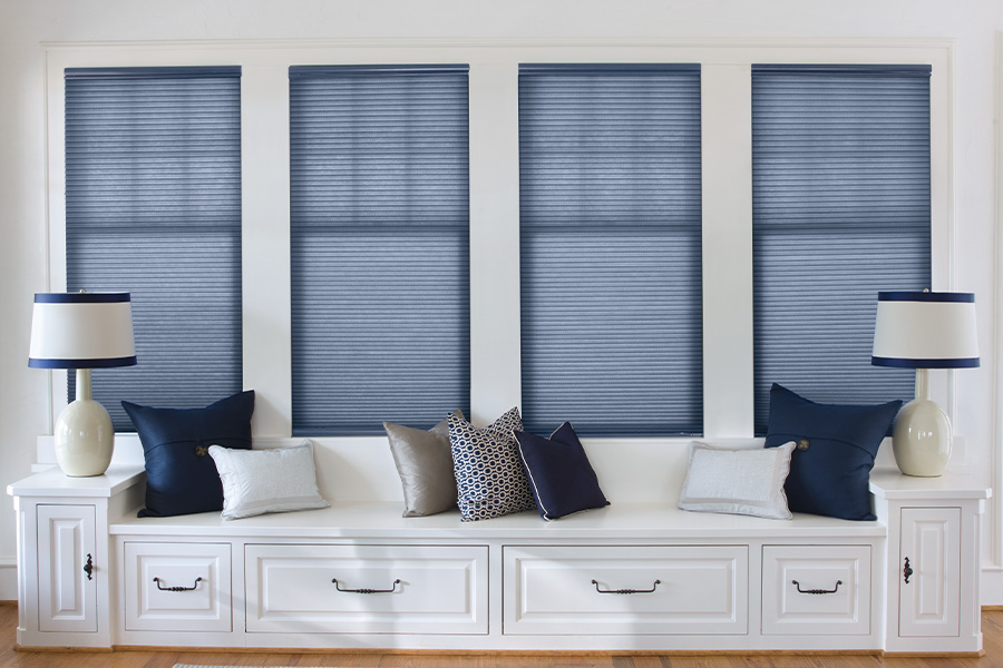 Colorful roller shades can tie a room together with function and style. Blue roller shades by a long window seating area.