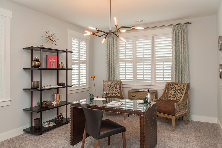 Colorful curtains can add a bit of flair with white Polywood shutters in San Antonio. Sage green patterned curtains on white polywood shutters in an office.
