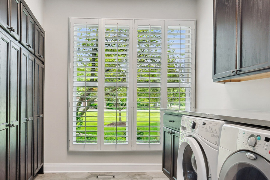 Find the perfect level of natural light for your San Antonio laundry room with interior shutters. White Polywood shutters letting light through a laundry room window