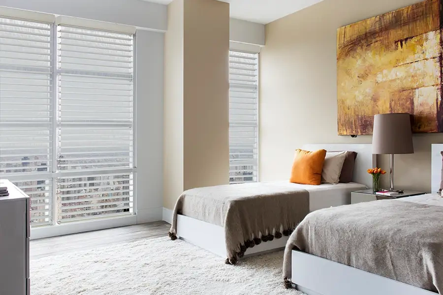 Sheer shades on tall windows in a bedroom with views of the city