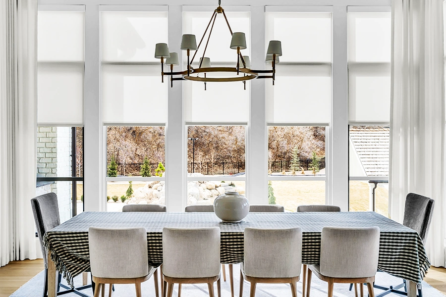Considering options like window shade opacity will help you find the ideal window treatment. Custom window shades and drapery in a formal dining area with large vertical windows